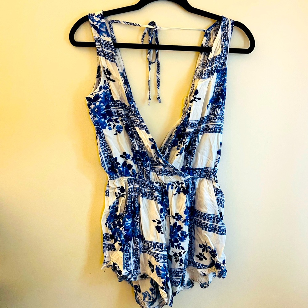 Adorable romper with pockets, ruffle trim, and tie back